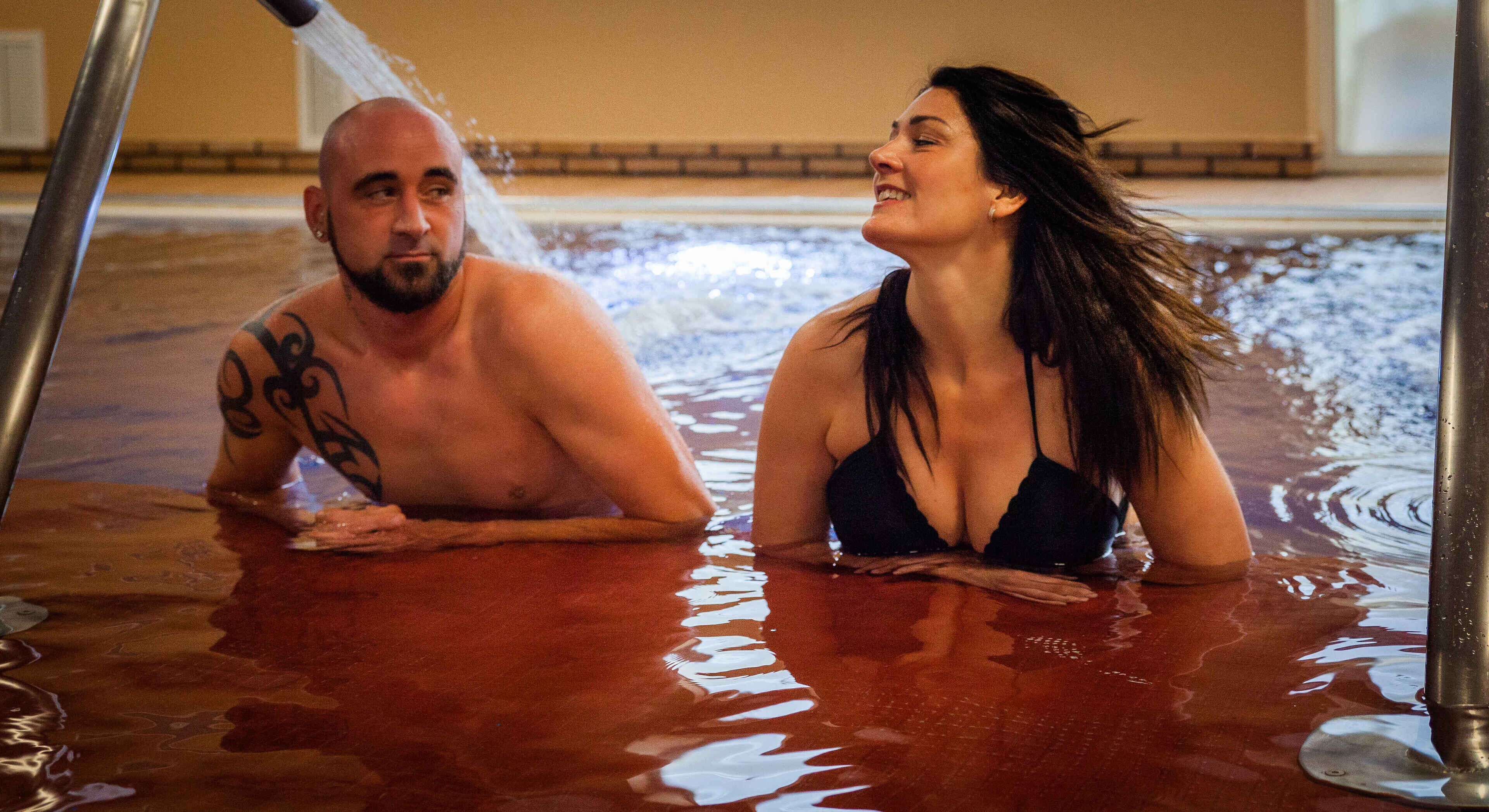 A man and a woman in a hot tub with water jets.