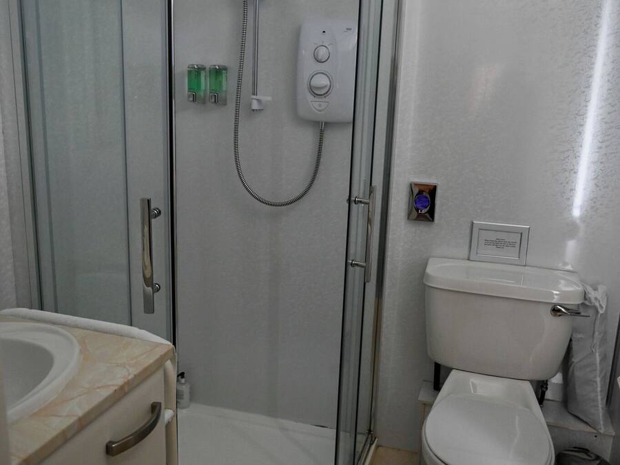 A modern bathroom with a glass-enclosed shower, a toilet, and a sink.