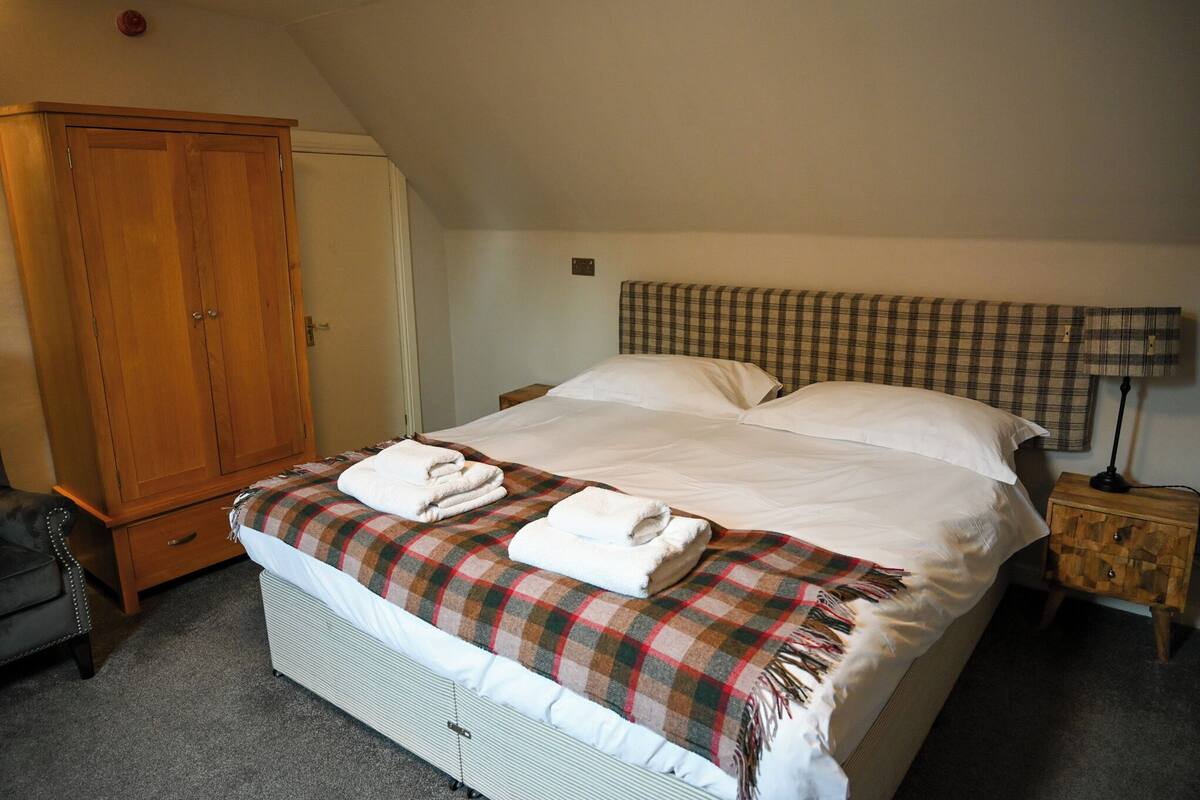 A bedroom with a bed, a wardrobe, a nightstand, and a lamp.