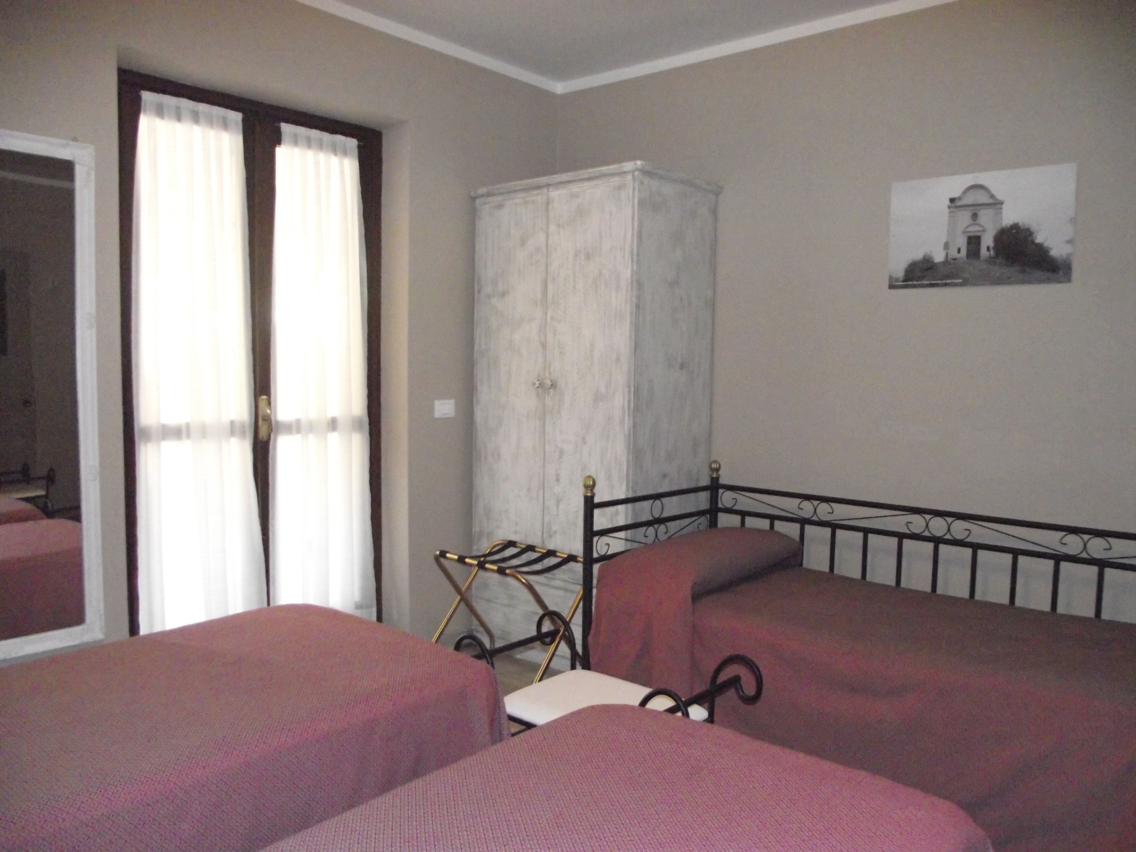 Un dormitorio con dos camas, un armario y un cuadro en la pared.