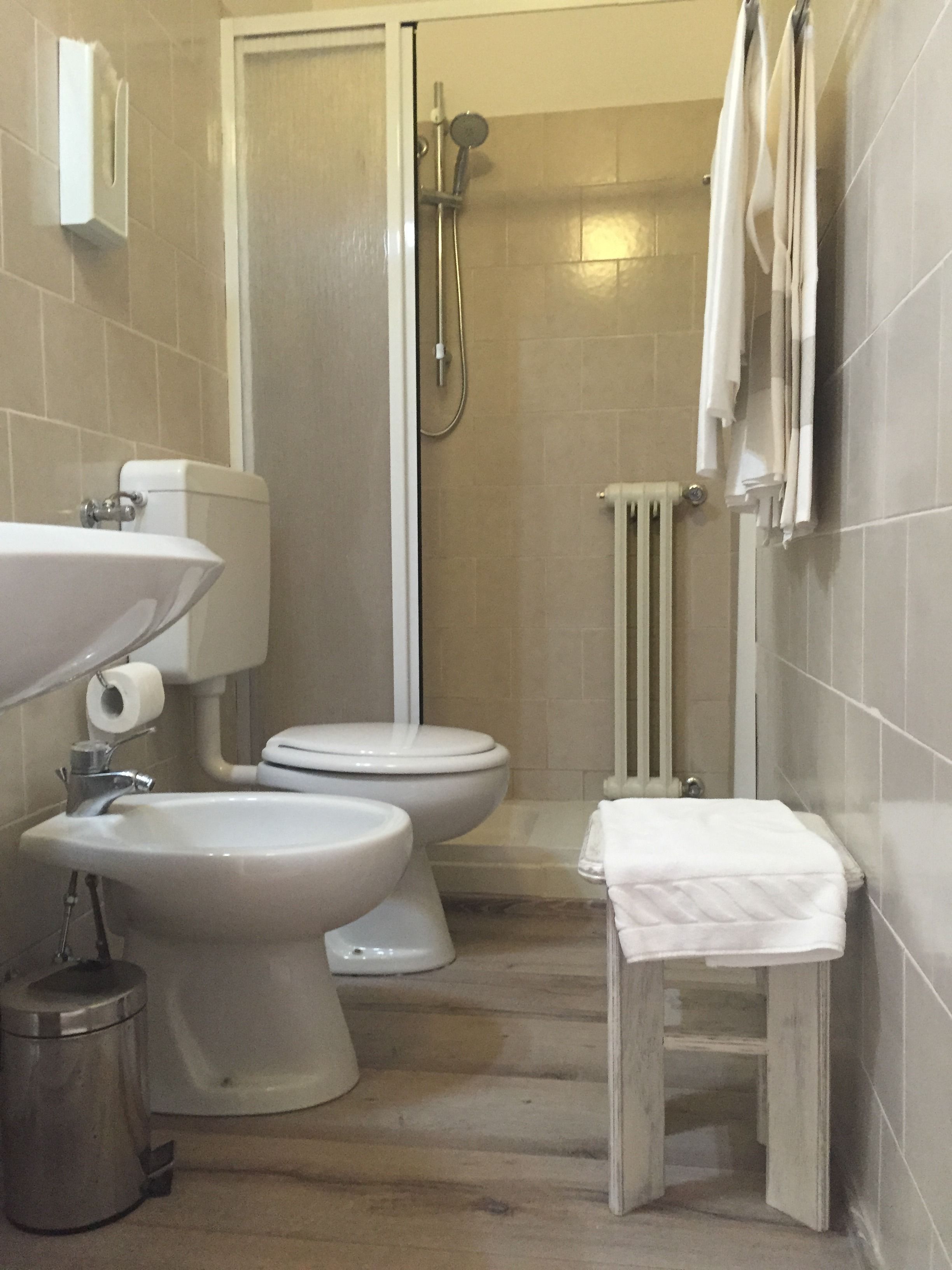 A bathroom with a toilet, bidet, sink, and shower.