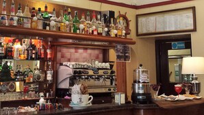 Angolo bar con diverse bottiglie di liquori, una macchina da caffè e un cartello con la scritta 'RC'.