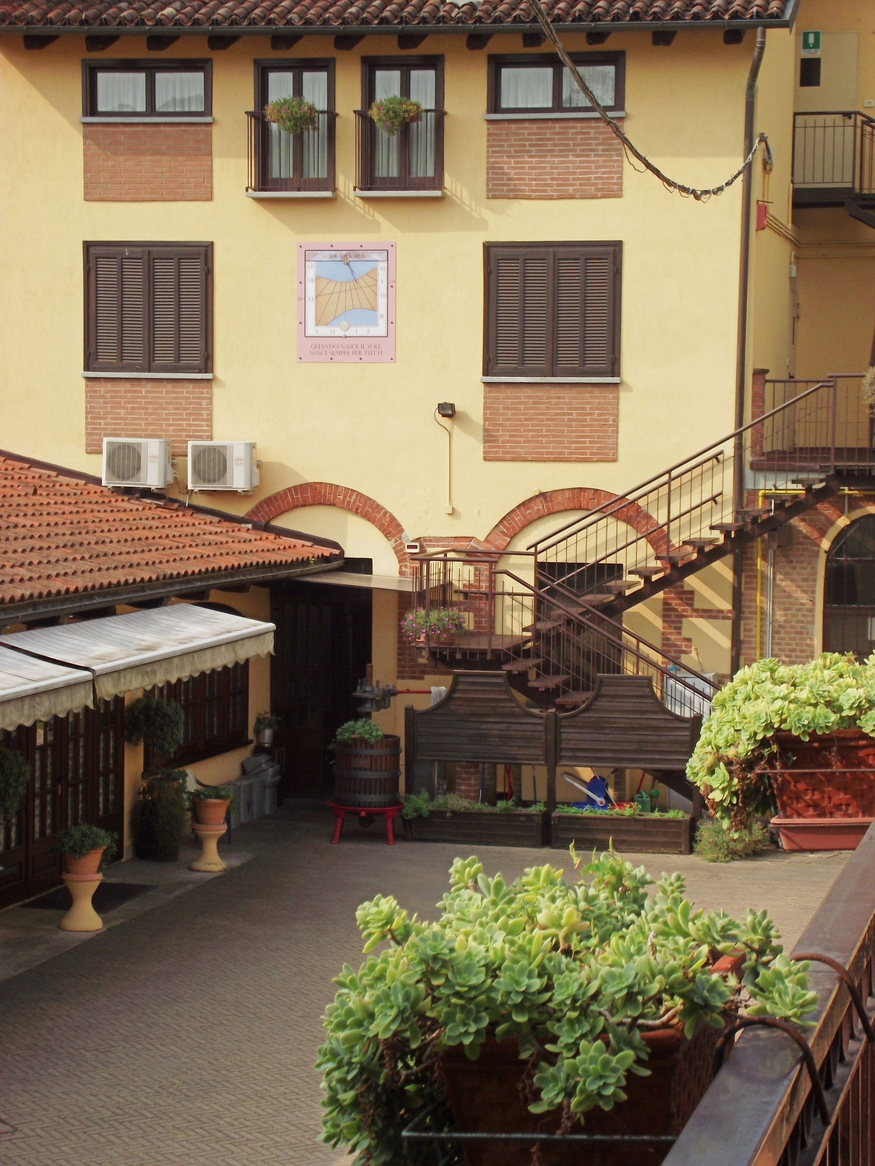 A courtyard with a brick staircase, potted plants, and a building with multiple windows and balconies.