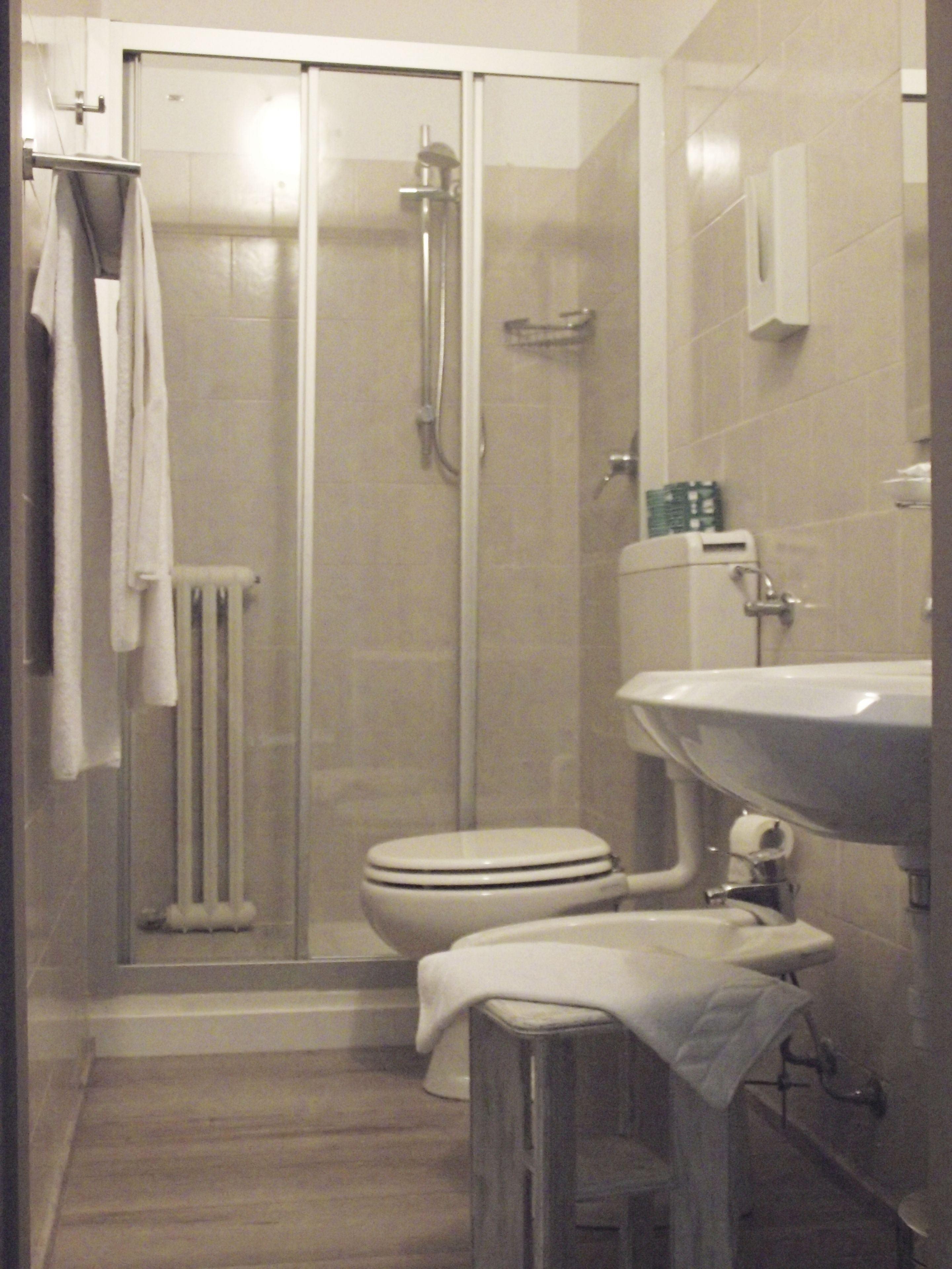 A bathroom with a glass-enclosed shower, a toilet, and a sink.