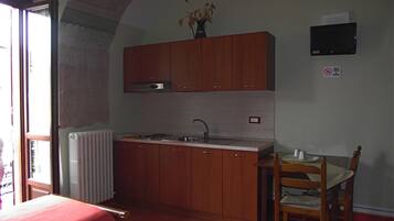 Eine kleine Küche mit Holzausbau, einem Einbauofen, einer Spüle und einem Essbereich mit Stuhl und Tisch.