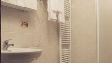 Une salle de bain équipée d’un lavabo, d’un porte-serviettes et d’une douche.
