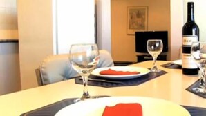 A dining table with plates, glasses, and a bottle of wine.