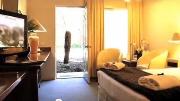 A hotel room with a bed, a desk with a computer, a chair, and a television.