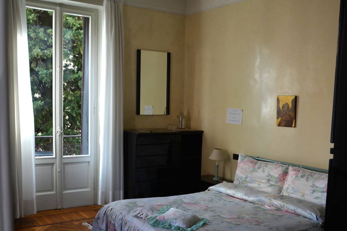 A bedroom with a bed, a dresser, a mirror, and a window.