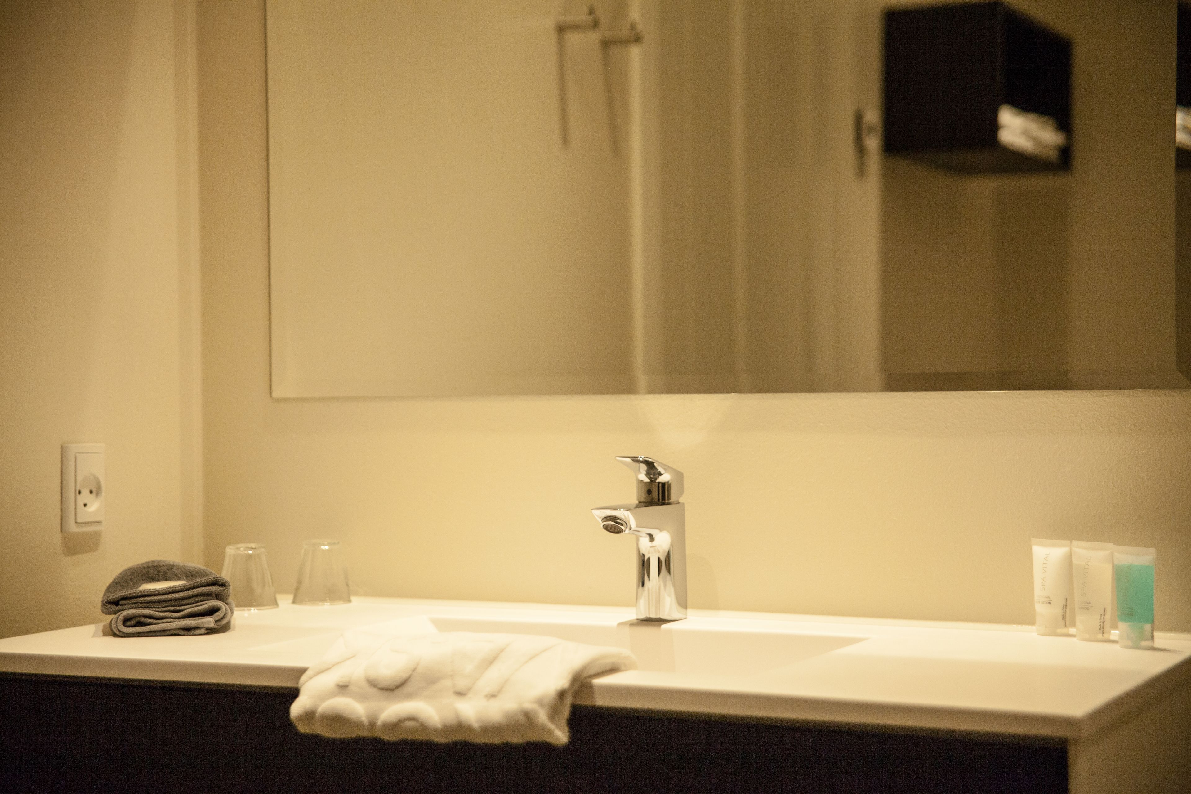 Un bagno con lavandino, specchio, asciugamano e articoli da toilette.