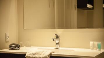 Un bagno con lavandino, specchio, asciugamano e articoli da toilette.