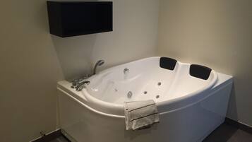 Un baño moderno con una bañera independiente, un estante en la pared y un perchero.