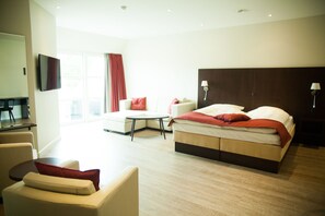 A hotel room with a bed, a sofa, a small table, and a TV.