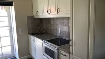 A kitchen with white cabinets, a granite countertop, a built-in oven, and a window with a view.