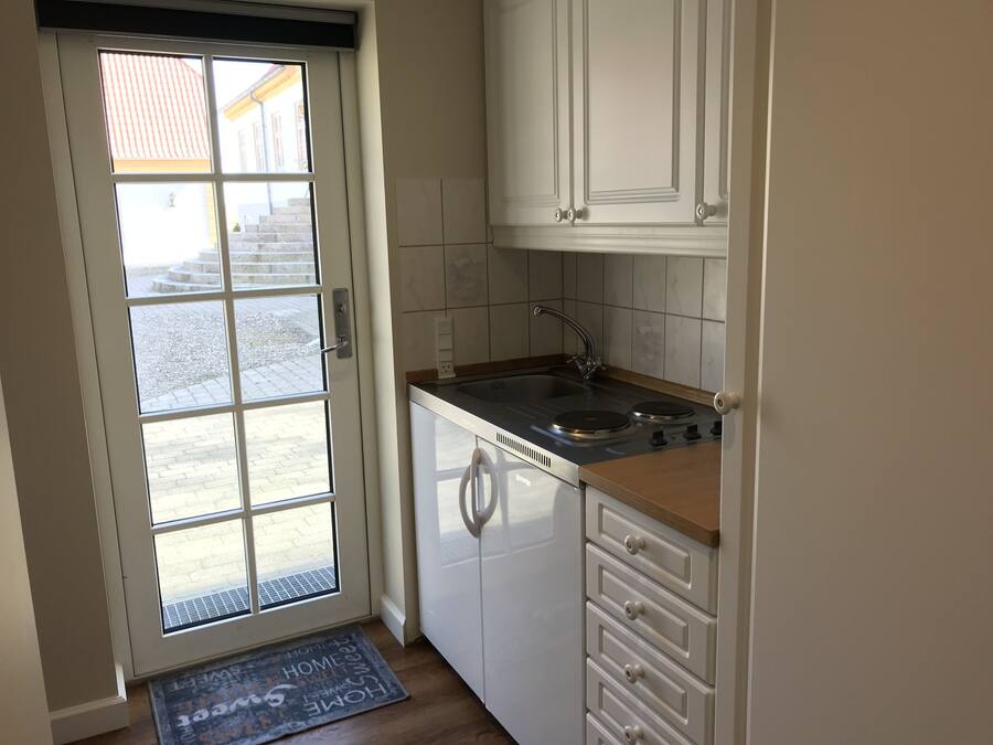 Een kleine keuken met een inbouwvaatwasser, een spoelbak en een raam met uitzicht op de straat.