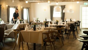 A restaurant with multiple tables set for dining, featuring a rustic interior with exposed brick walls and hanging pendant lights. - Hotel BramslevGaard (Hobro)