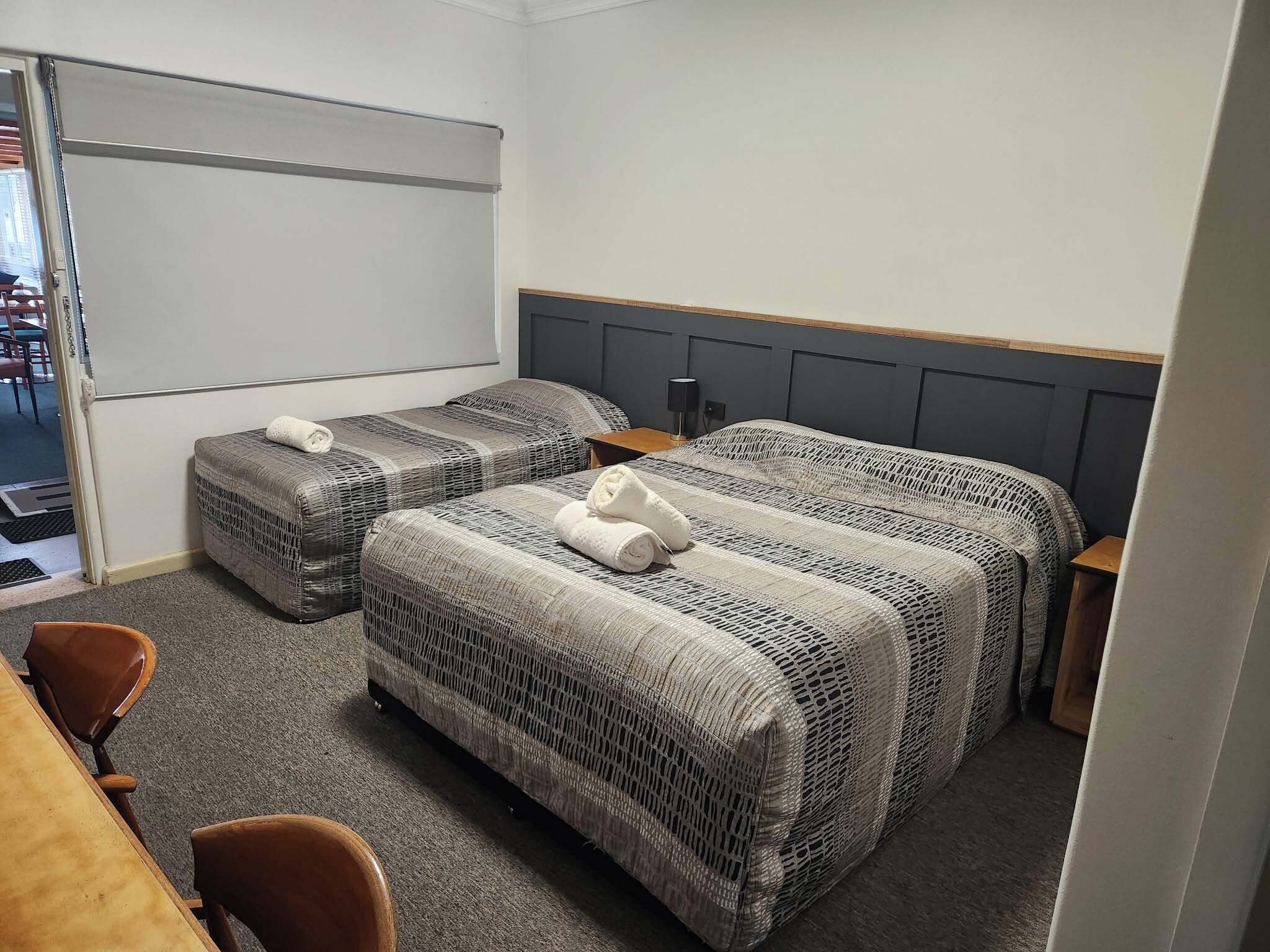 Quarto de hotel com duas camas, uma escrivaninha e uma cadeira.