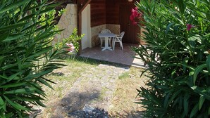 A rustic building with a stone facade, a tiled roof, and a small patio with a table and chairs. - Tenuta Molino di Mare - Ecoresort with Villini (Rodi Garganico)