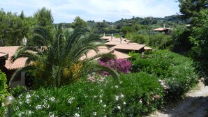 A villa with a tiled roof, surrounded by lush greenery and flowering plants. - Tenuta Molino di Mare - Ecoresort with Villini (Rodi Garganico)