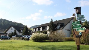 A signpost with directional information for nearby locations, a row of houses, and a car parked in front. - Landhotel Pockau (Lengefeld)