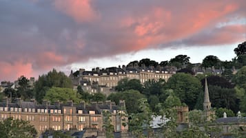 A town with terraced houses, a church spire, and a hill with trees.