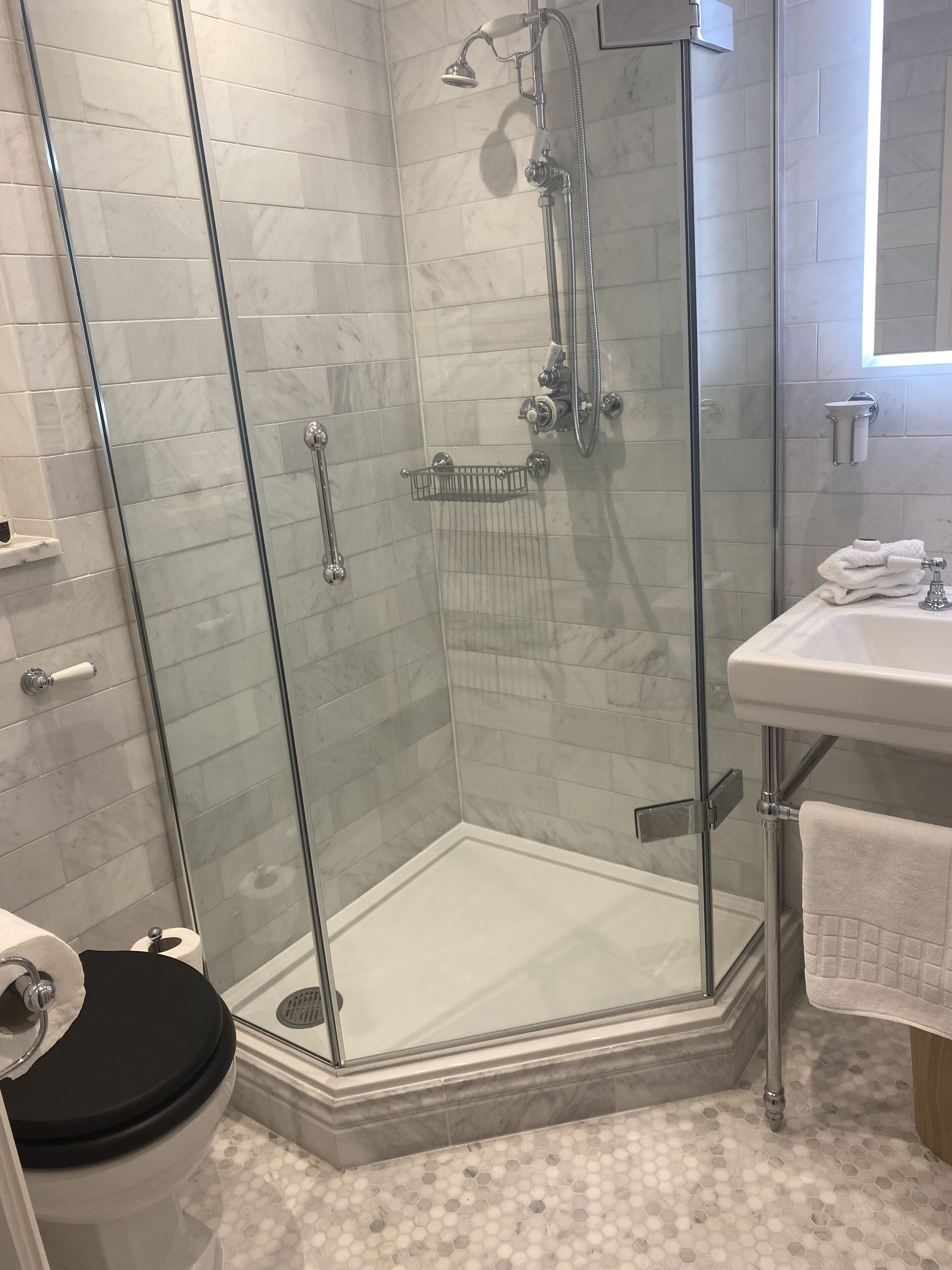 Un bagno moderno con doccia vetro-muraria, un water e un lavandino.