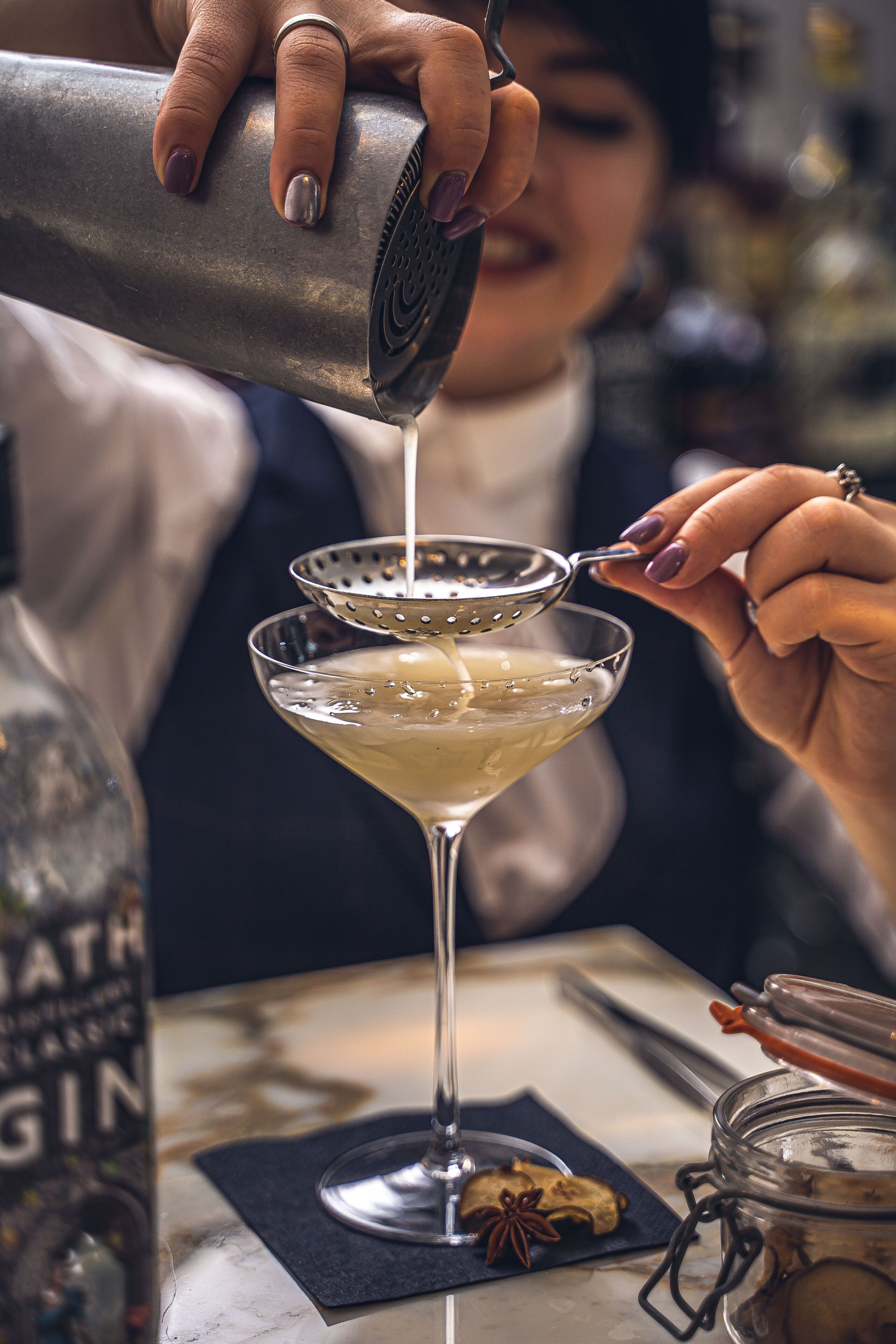 A bartender pouring a drink into a martini glass.