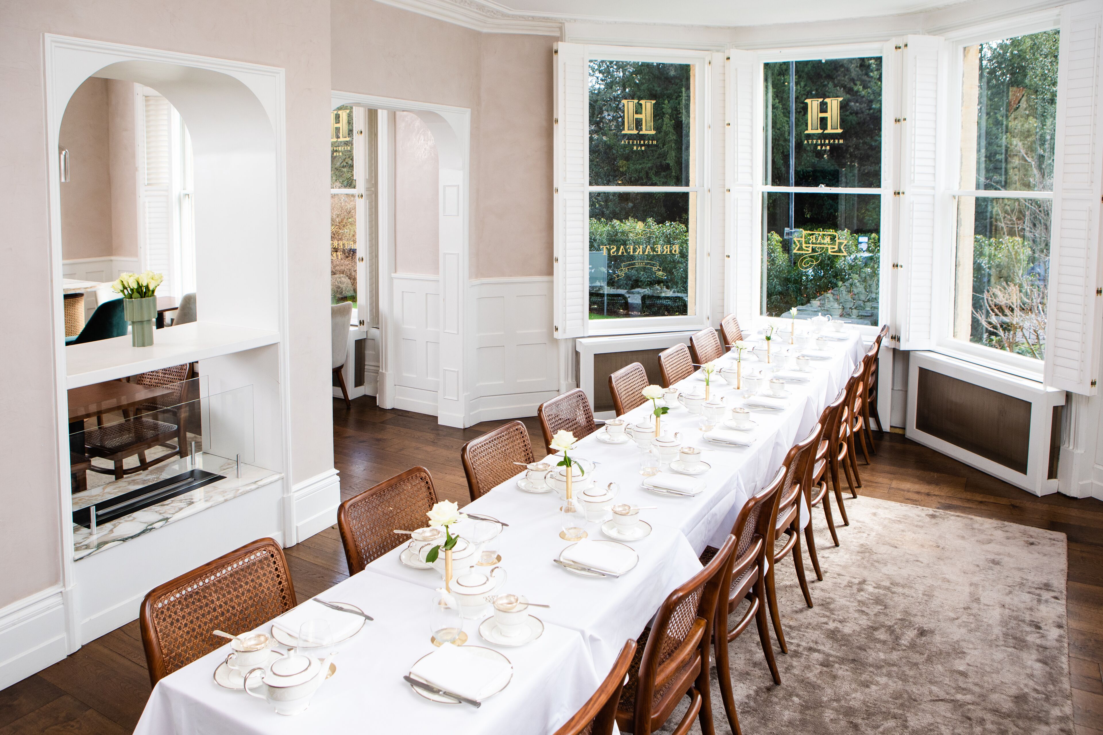 A dining room with a long table set for a meal, surrounded by wooden chairs.