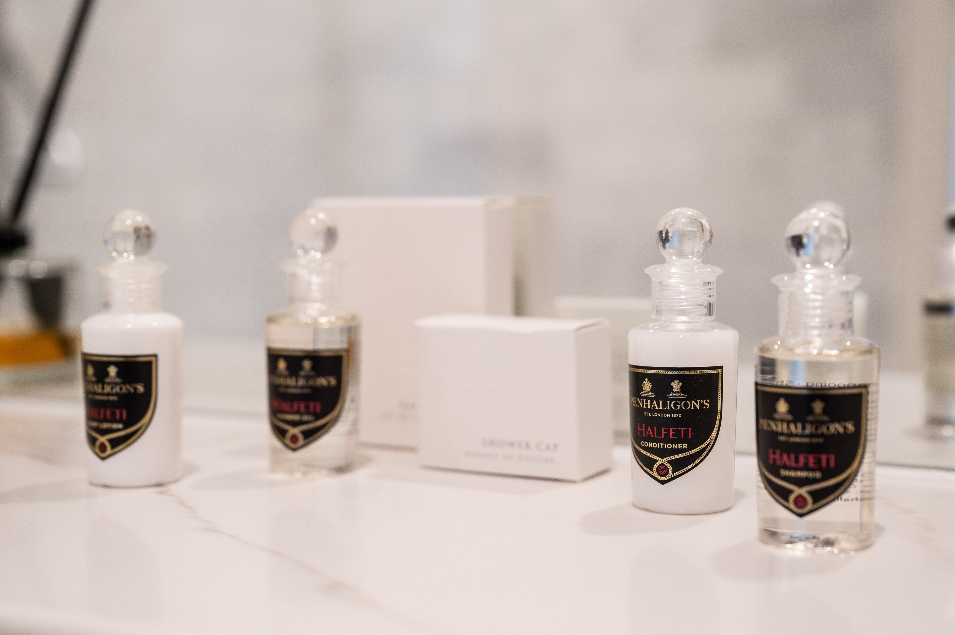 Four bottles of Hufetii conditioner and a box of Shower Cap on a marble surface.