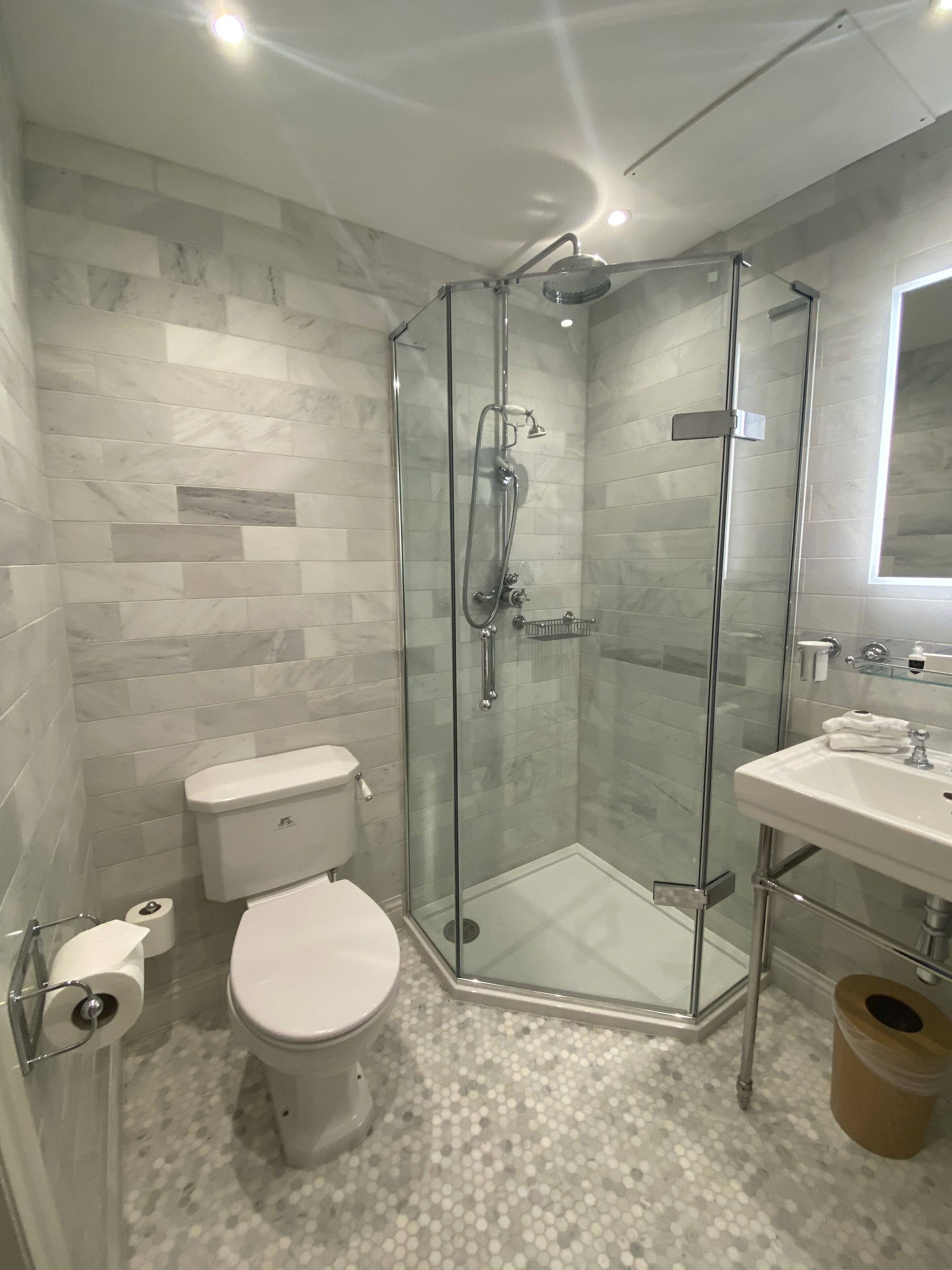 A modern bathroom with a glass-enclosed shower, a toilet, and a sink.