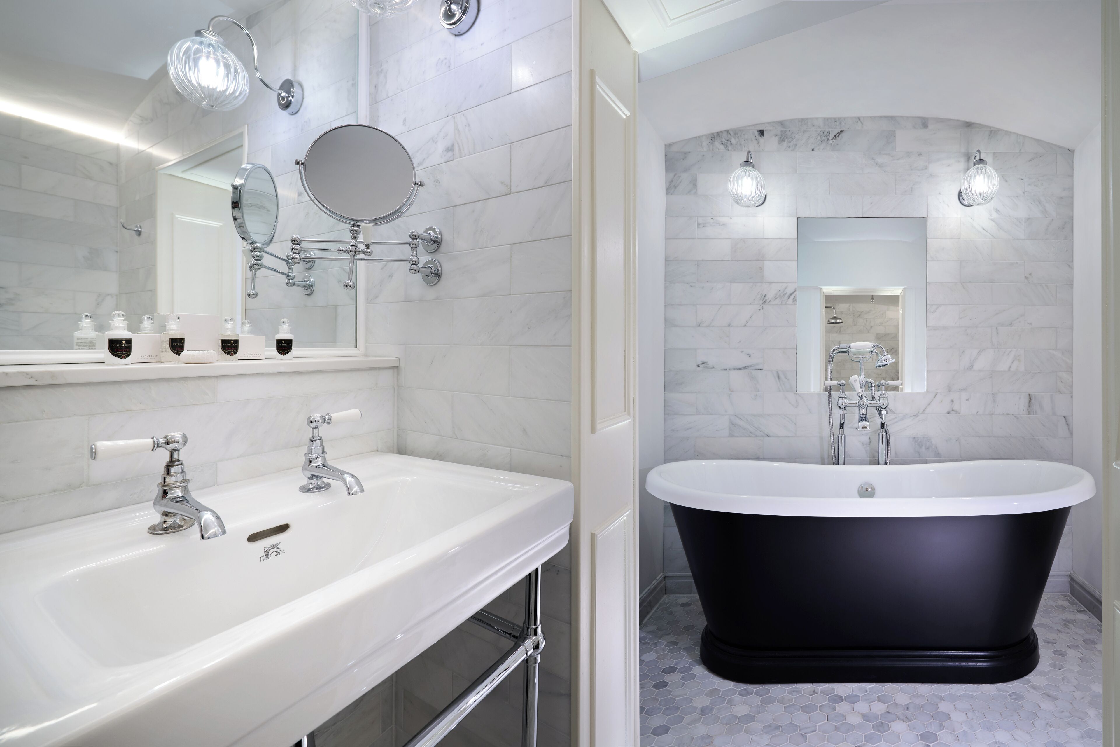 A modern bathroom with a white vanity, a black freestanding bathtub, and a large mirror.