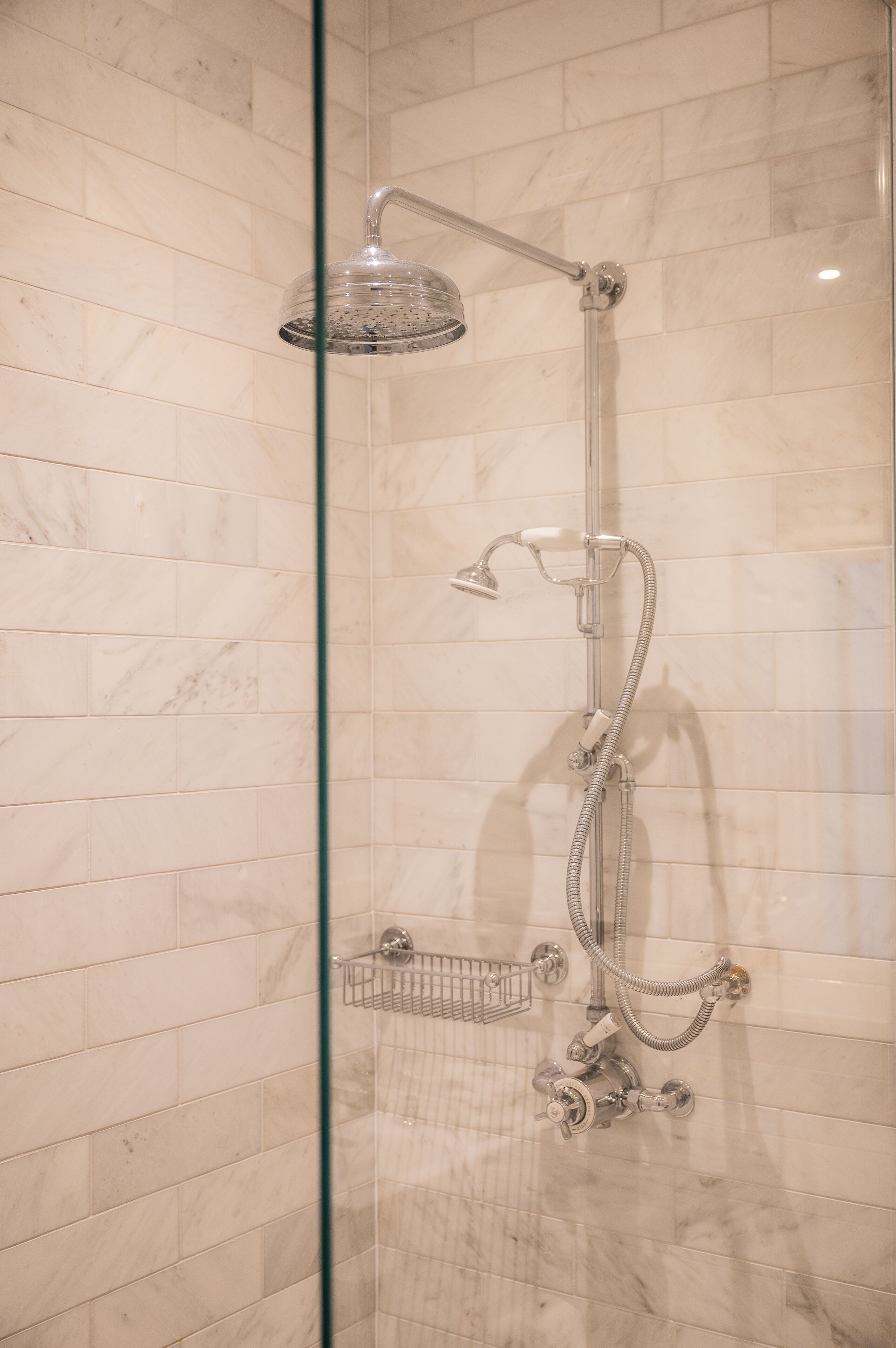 Een douche met glazen wand, een handdouche, een wandmengkraan en een extra douchestraal.