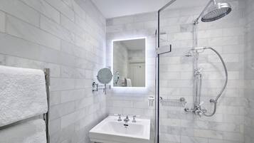 Un baño moderno con ducha envuelta en vidrio, un lavamanos blanco y un espejo sobre él.