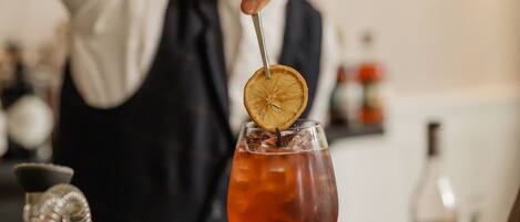 A bartender preparing a cocktail with a garnish in a glass.