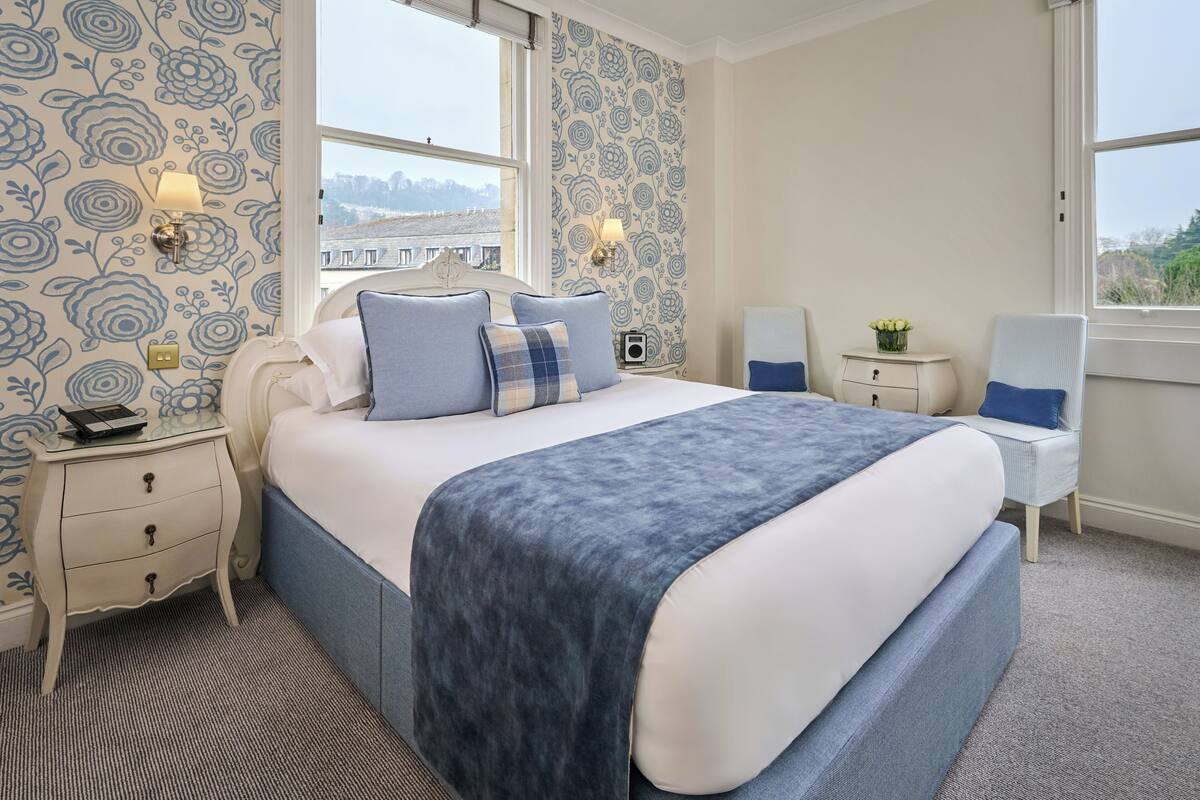A neatly arranged bedroom with a large bed, bedside tables, and a chair.