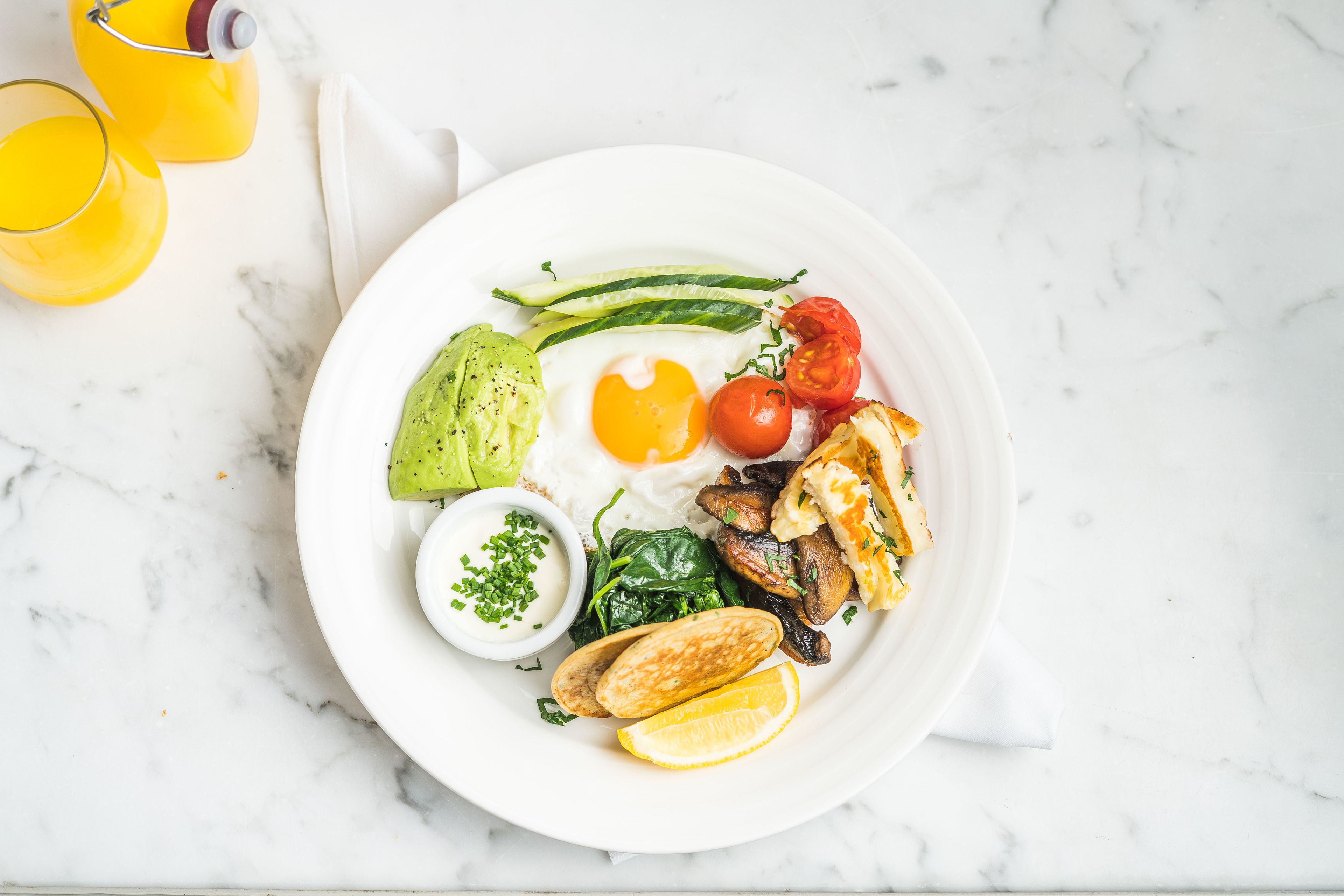 A plate of food with a variety of items including eggs, vegetables, and a glass of orange juice.