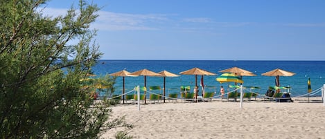 Una playa con sombrillas y sillas de descanso.
