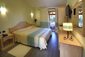 Ein Hotelzimmer mit Bett, Nachttisch, Lampe und Fernseher.
