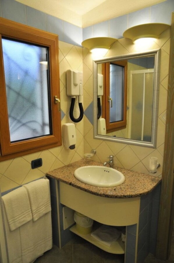 A bathroom with a sink, mirror, towel rack, and a telephone.