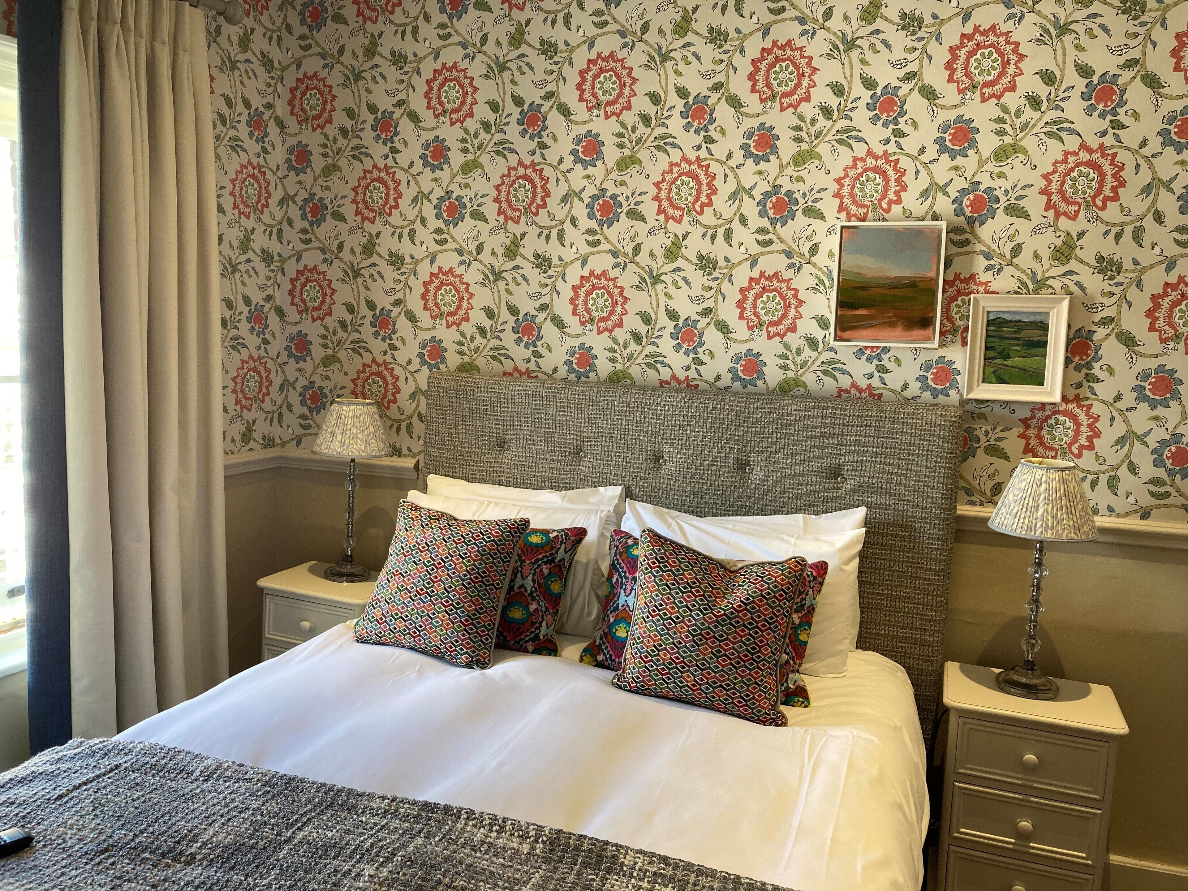 A neatly made bed with patterned pillows, a headboard, and two bedside tables with lamps.