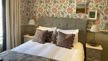 A neatly made bed with patterned pillows, a headboard, and two bedside tables with lamps.