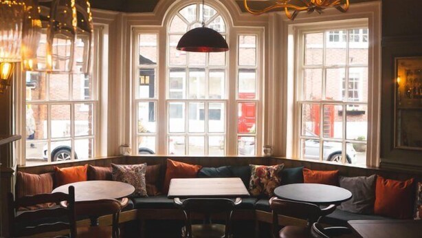 Un restaurante acogedor con una zona de estar central, ventanas amplias y un candelabro.