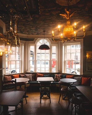 Un restaurant accueillant, doté d’un espace de restauration central, de grandes fenêtres et d’un lustre.