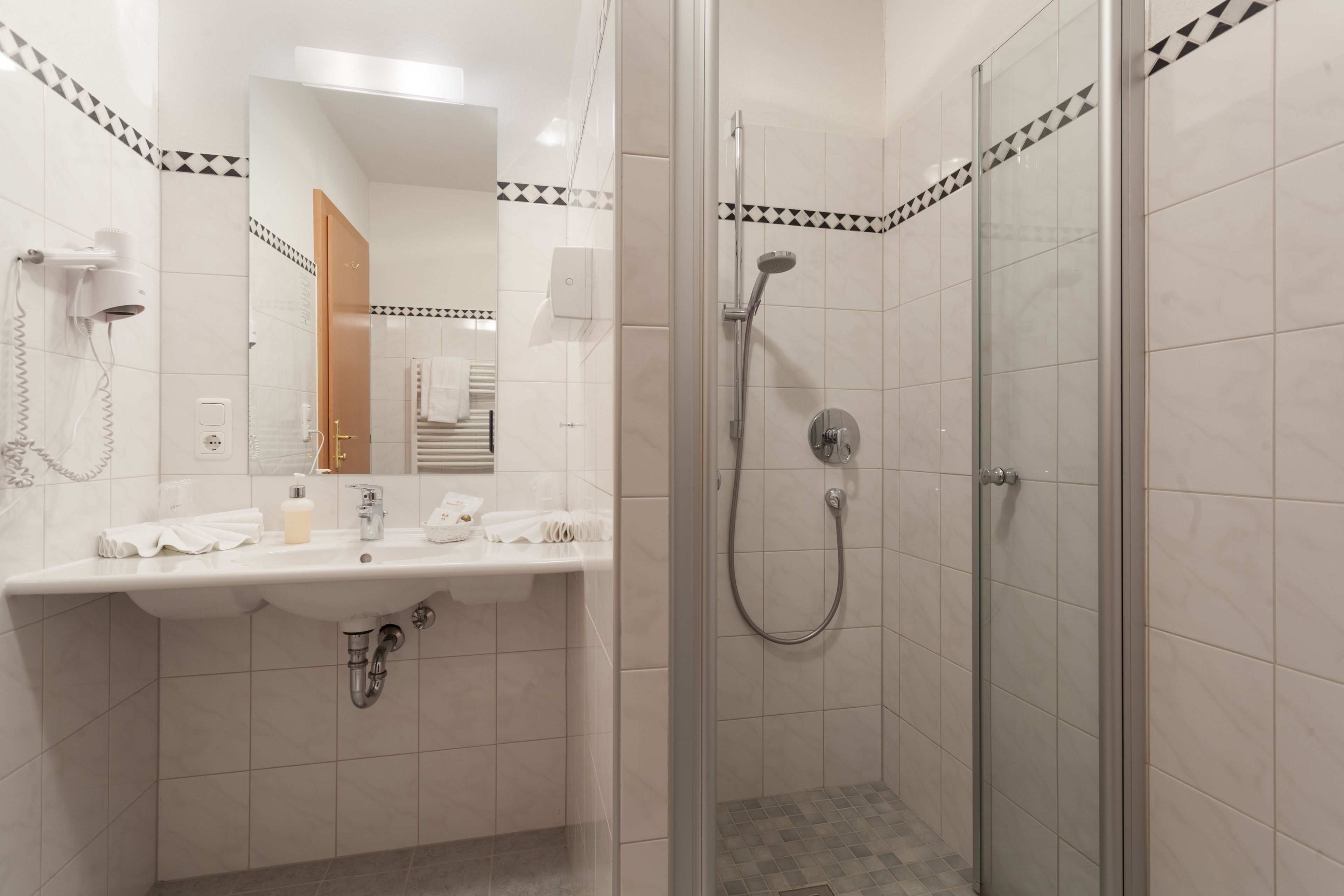 Un baño moderno con lavamanos, espejo y ducha.