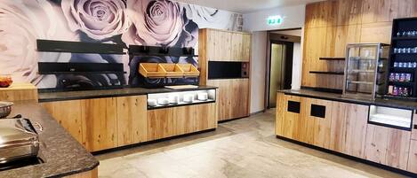 A modern kitchen with wooden cabinets, a black countertop, and a floral mural on the wall.