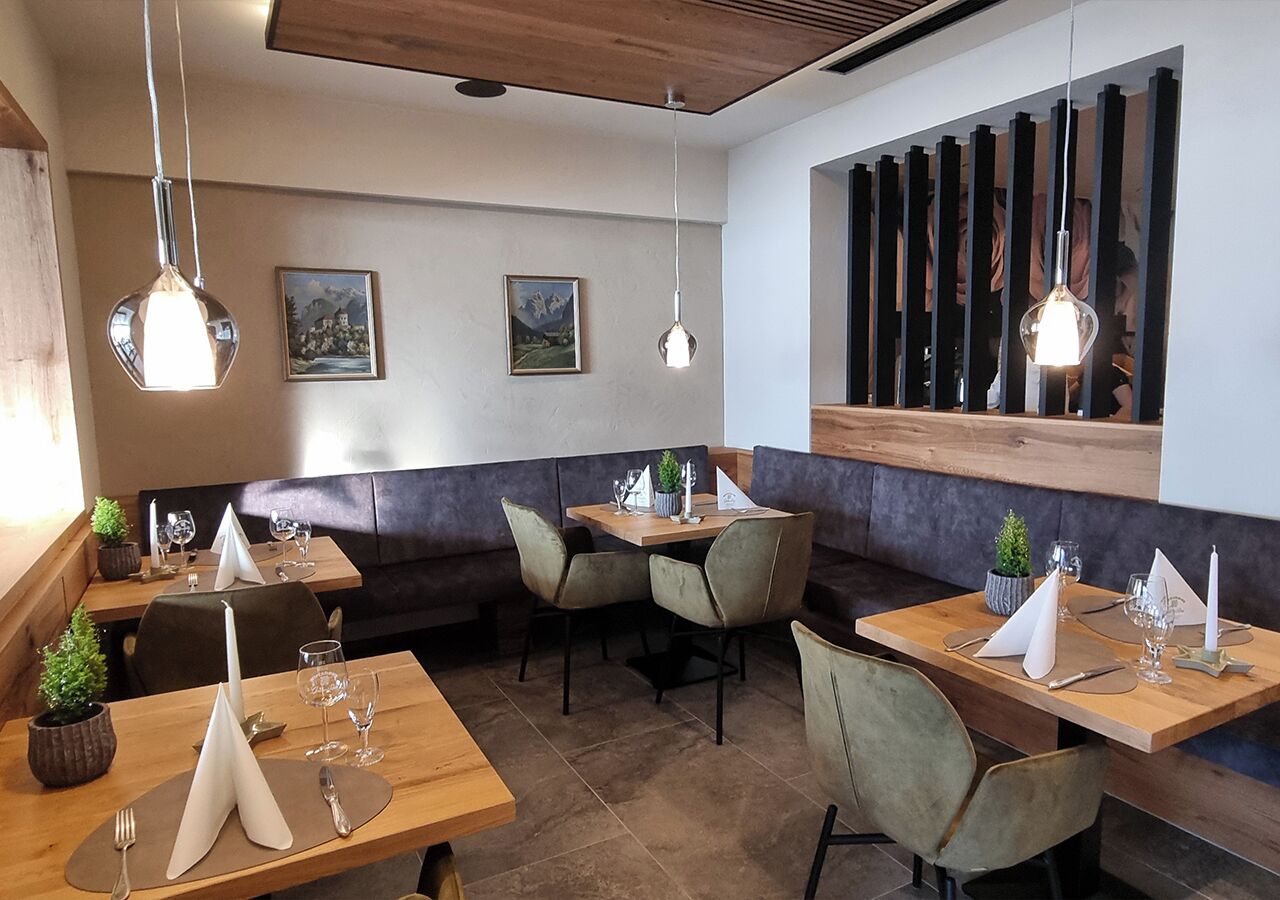 A restaurant with wooden tables and chairs, pendant lighting, and framed pictures on the walls.