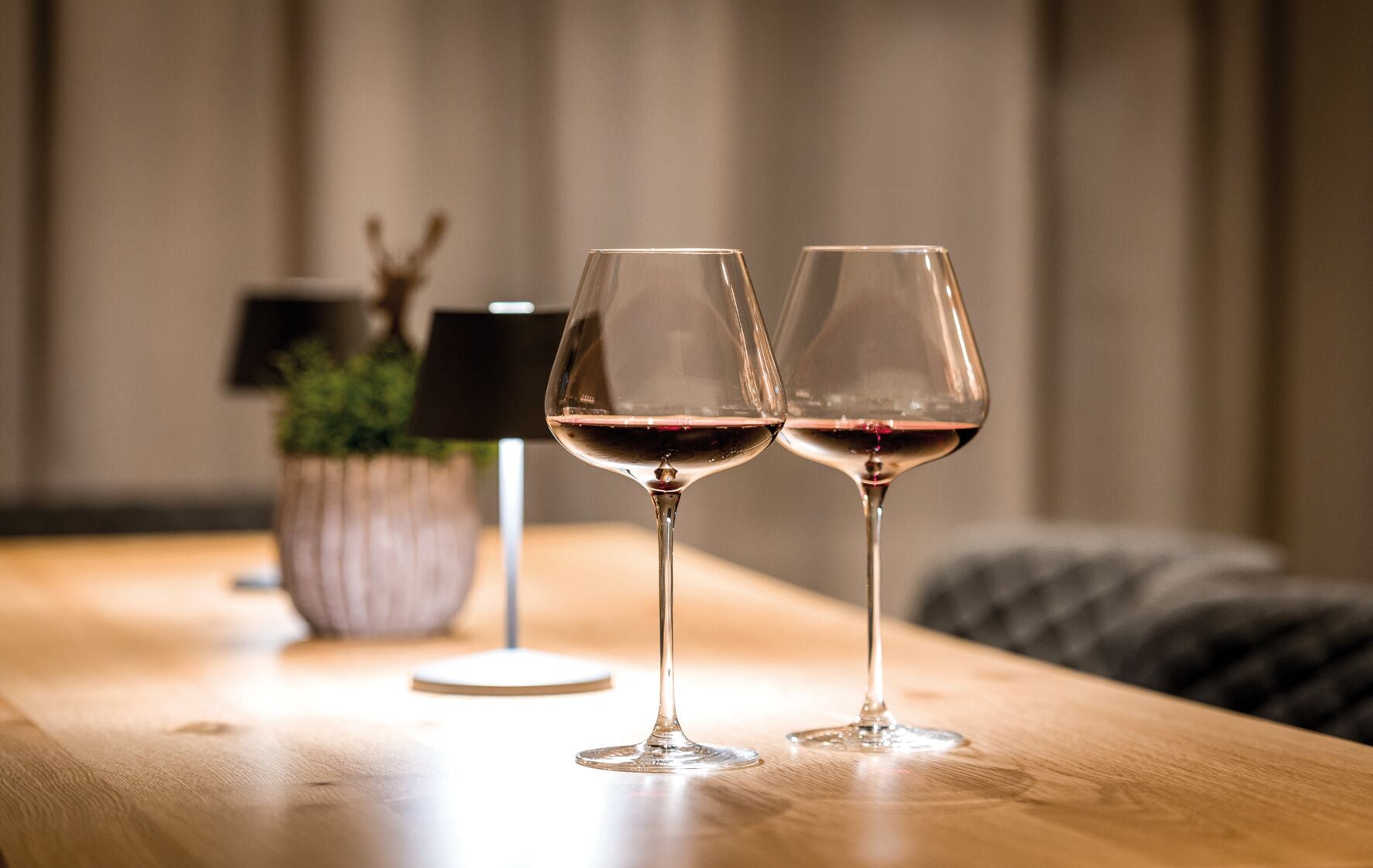 Duas taças de vinho sobre uma mesa de madeira, com fundo desfocado.
