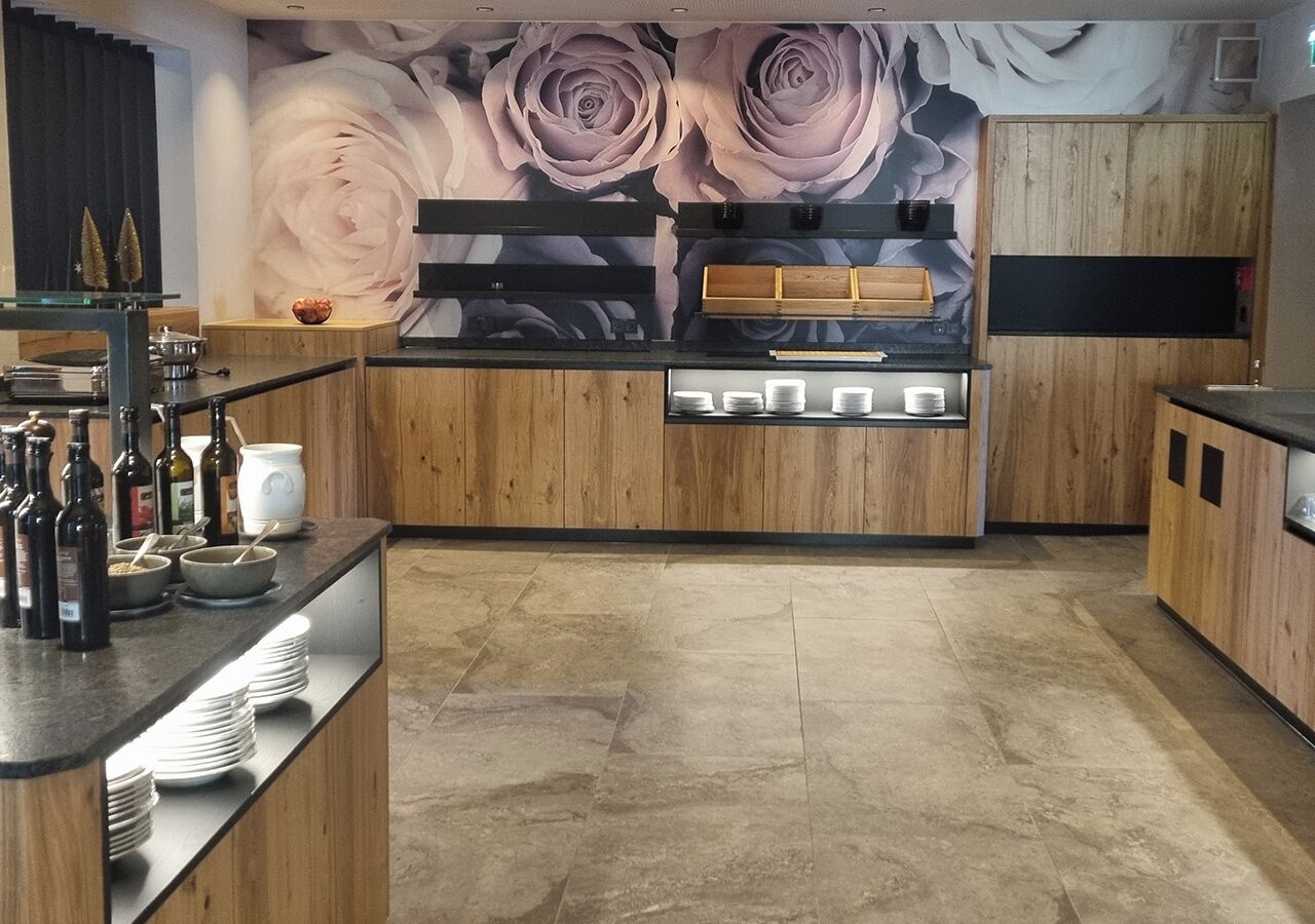 A modern kitchen with wooden cabinets, a marble countertop, and a floral mural on the wall.