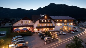 A hotel with a restaurant and café, parking area, and mountainous backdrop. - Hotel Goldene Rose (Lechaschau)