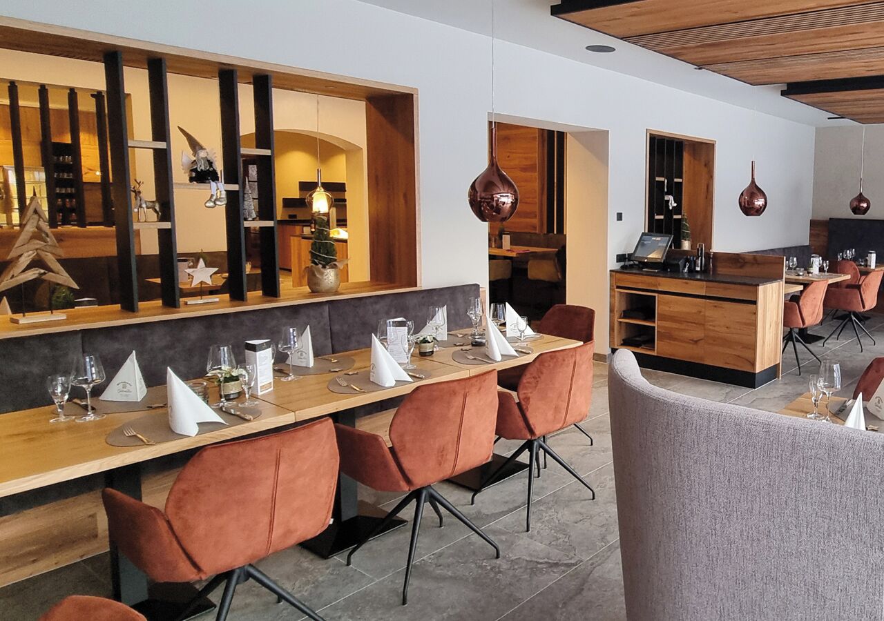 A modern dining area with a long wooden table set for a meal, surrounded by cushioned chairs.